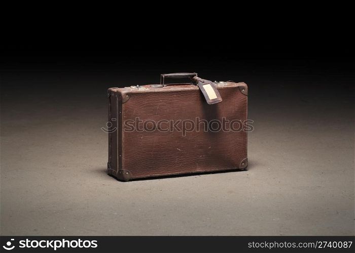 Old brown suitcase abandoned on dirty concrete floor