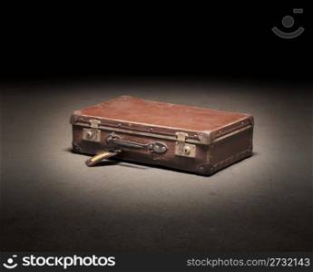 Old brown suitcase on dirty concrete floor