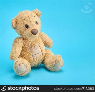 old brown teddy bear on a blue background, copy space