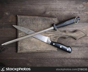  old brown wooden cutting board and knife with sharpening on the table, top view