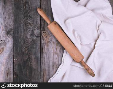old brown wooden rolling pin on a gray linen napkin, top view