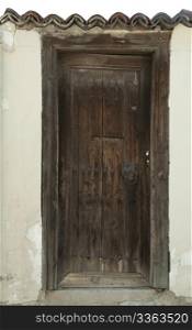 Old brown wooden vertical door. White wall