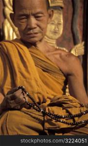 Old Buddhist Monk holding Beads