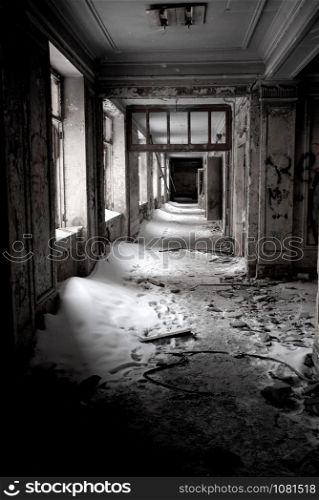 old building after fire in winter time with white snow inside and broken windows. white walls with black traces of fire