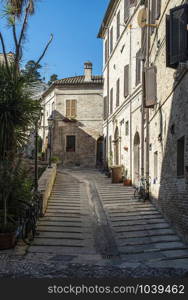 Old buildings on small italian street. Narrow street in Italy. Flowers in front of vintage houses.