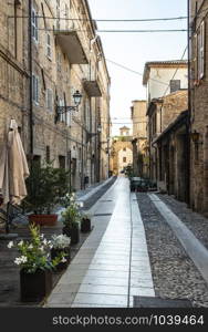 Old buildings on small italian street. Narrow street in Italy. Flowers in front of vintage houses.