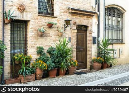 Old buildings on small italian street. Narrow street in Italy. Flowers in front of vintage houses.