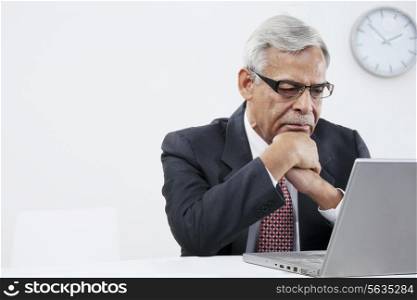 Old businessman looking at a laptop