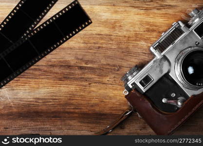 old camera and blank film strip on wooden table