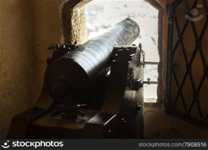 Old cannon pointing through embrasure at ancient castle