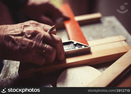 Old carpenter taking measurement of a wooden plank, retro tinted