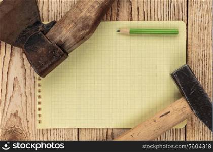 Old carpentry tools and a piece of notebook on a wooden background. carpentry tools on a wooden background