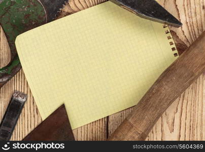 Old carpentry tools and a piece of notebook on a wooden background. carpentry tools on a wooden background