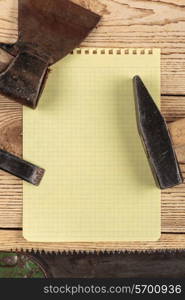 Old carpentry tools and a piece of notebook on a wooden background. carpentry tools on a wooden background