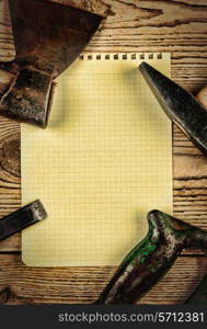 Old carpentry tools and a piece of notebook on a wooden background. carpentry tools on a wooden background