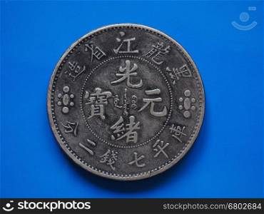 Old chinese coin over blue. Vintage silver Chinese 7 mace and 2 Candereens coin from the Lung Kiang Province in China, Circa 1889 Over Blue Background