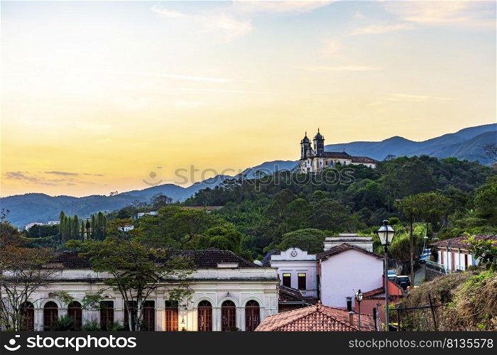 Old church on top of the hill with the city of Ouro Preto, hills and vegetation around during the sunset. Old church on top of the hill in the city of Ouro Preto
