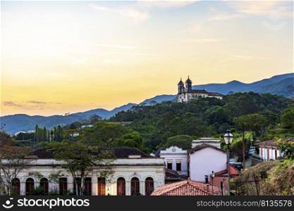 Old church on top of the hill with the city of Ouro Preto, hills and vegetation around during the sunset. Old church on top of the hill in the city of Ouro Preto