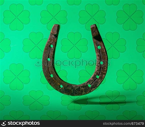 old classic horseshoe symbol of good luck on top of a bright green background with clover leaves. horseshoe green background