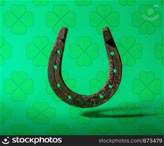 old classic horseshoe symbol of good luck on top of a bright green background with clover leaves. horseshoe green background