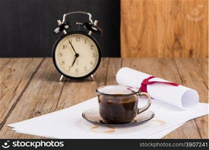 Old clock, hat, coffee and paper sheets on old Wooden table.
