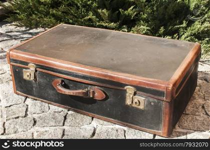 Old closed locked retro vintage leather suitcase on stone paved surface closeup