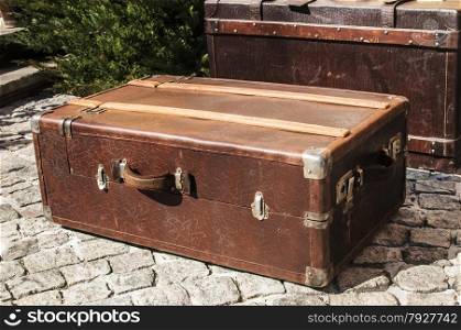 Old closed locked retro vintage leather suitcases on stone paved surface closeup