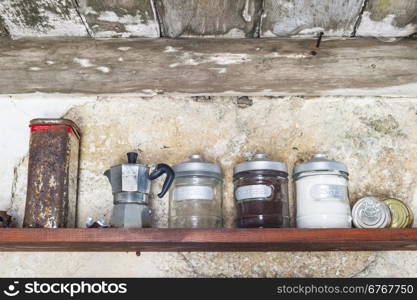 Old coffeepot on a shelf with cans of coffee, sugar and salt and old tin box