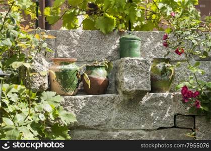 Old colorful clay pots placed in niche of granite block stone garden wall