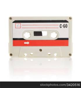 Old compact cassette audio tape isolated on white with natural reflection.