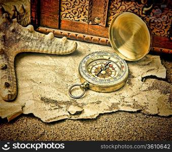 Old compass and old torn paper on a sandy beach