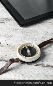 old compass and tablet PC on bright wooden background. compass and tablet