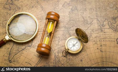 Old compass , magnifying glass and sand clock on vintage map
