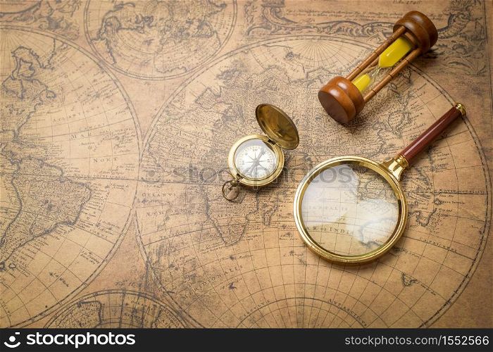 Old compass , magnifying glass and sand clock on vintage map