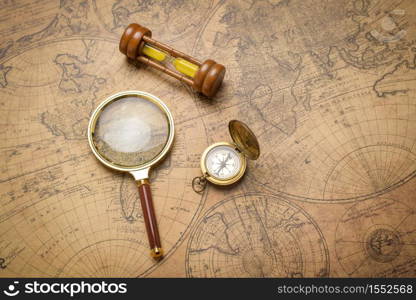 Old compass , magnifying glass and sand clock on vintage map