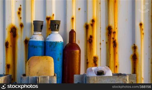 old compressed liquid air bottles standing in front of a rusty container, Industrial background