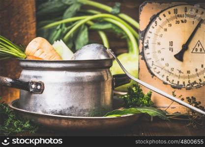 Old cooking pot with raw vegetables and ladle on rustic kitchen table , front view