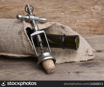 Old corkscrew and bottle of wine on the board