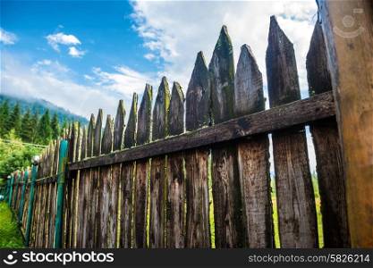 Old country fence with forest and blue sky on background