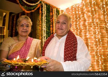 Old couple holding a tray of diyas