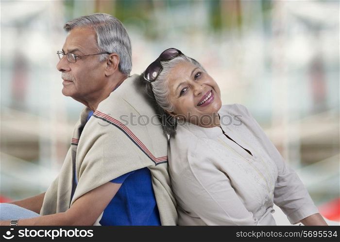 Old couple sitting back to back