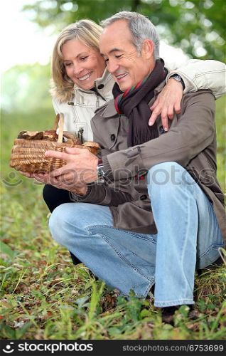 old couple watching a wickerwork basket of mushrooms in the countryside