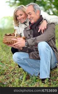 old couple watching a wickerwork basket of mushrooms in the countryside