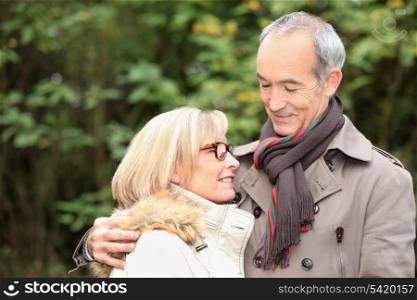 old couple wearing warm clothes in the forest and expressing tenderness