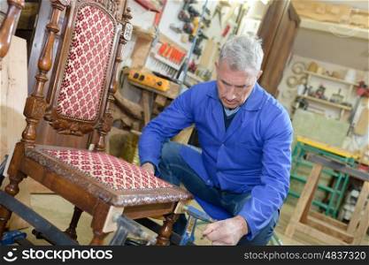 old craftsman repairing a chair in his workshop