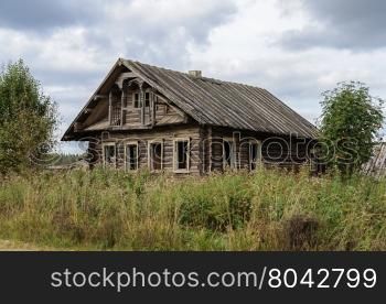Old destroyed log wooden house in russian village, Vologda region. Summer day