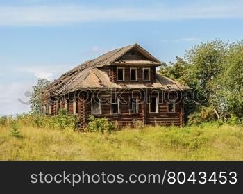 Old destroyed log wooden house in russian village, Vologda region. Sunny summer day