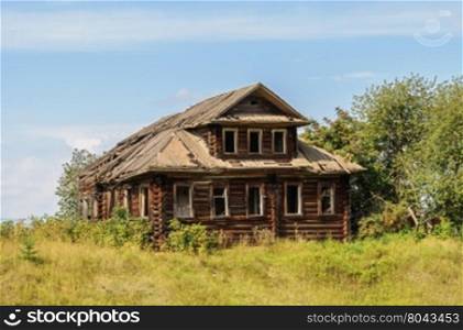Old destroyed log wooden house in russian village, Vologda region. Sunny summer day
