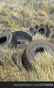 Old dirty abandoned tires in field.