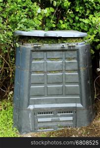 Old dirty composter bin with rotten grass.